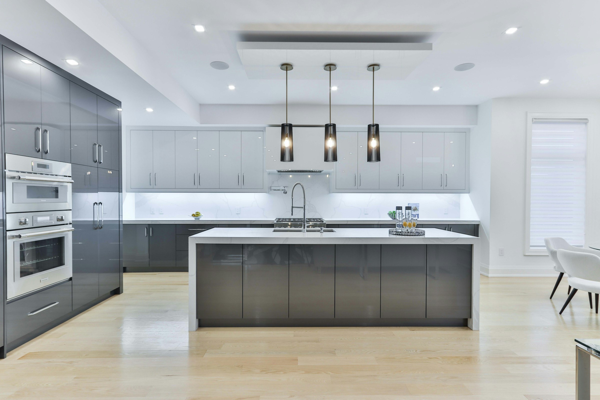 Modular kitchen with grey cabinets, a white island and pendant lights